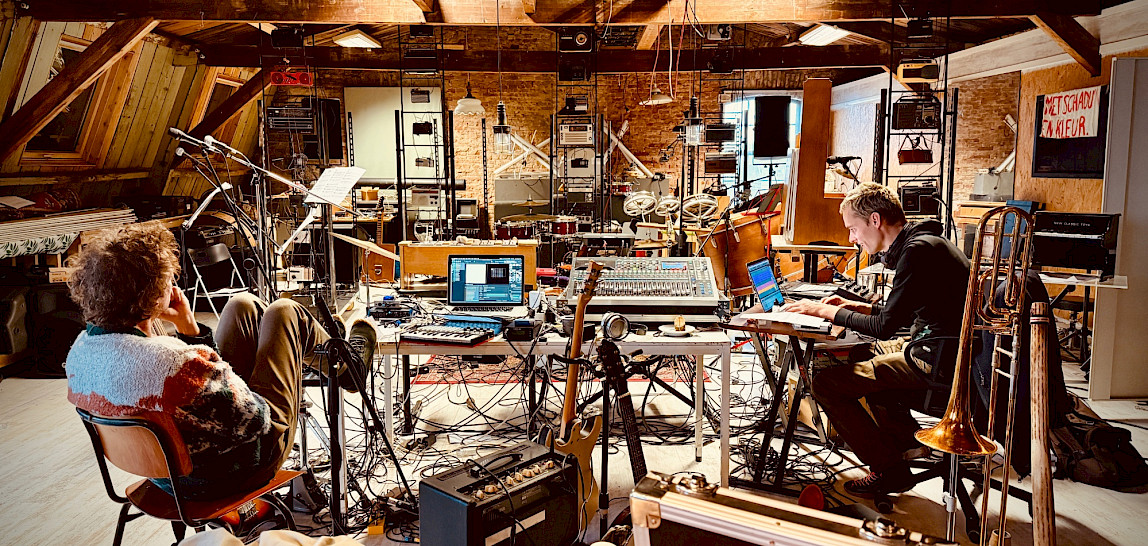 Muzikanten van Veenfabriek werken tussen instrumenten en geluidsapparatuur in de monumentale zolder van Scheltema in Leiden. Foto: Yonga Sun